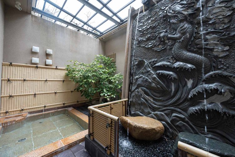 開運効果もバッチリ？　男湯の打たせ湯は石壁に登り龍、女湯は登り鯉が彫られている。