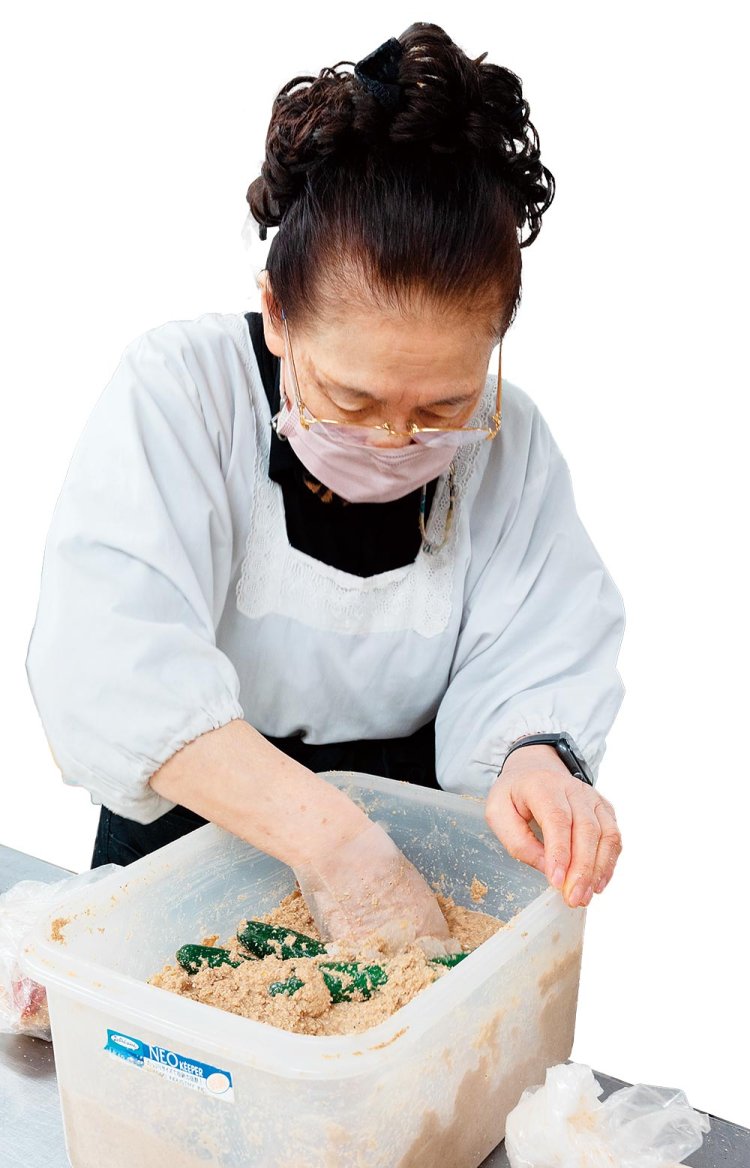 割烹着姿でぬか床を混ぜる絹子さん。