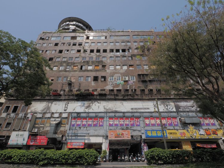 千越大楼の全景。1階と2階が営業中で、その上階が朽ちているという異様な姿。屋上に突出しているのが回転レストランのあった展望フロア。