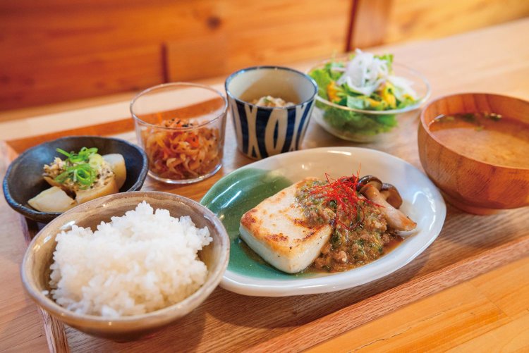 『食堂 よろしき日』の藤田寛さん・紀世さんオーナー夫妻（上）。この日の定食のメインは豆腐ステーキに葉ニンニクの味噌ソース。新じゃが野沢菜漬け、大根と雪下にんじんなどの小鉢が並ぶ。