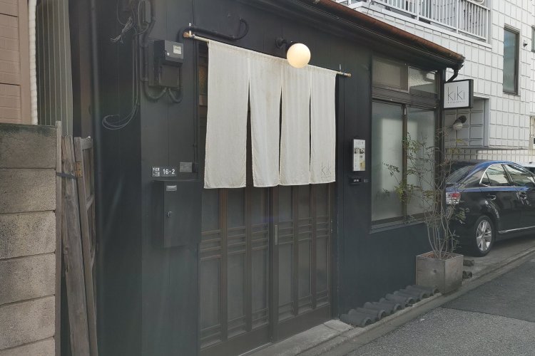 閑静な住宅地の一角にある古民家カフェ。黒い外壁に白いのれんや看板が映える。