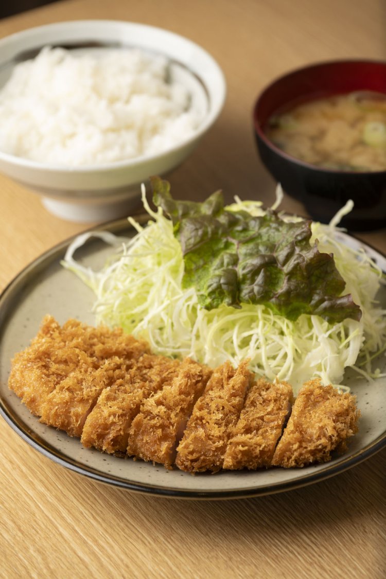 ロース(100g)定食1050円。とんかつの上下がピシッと揃ったこの美しさ。しかし実はこれ、脂身の方が手前を向いているのだ。「脂身を下にした方が油がよく切れて、そのまま配膳するとこうなる」とのことだが、食べる際に脂の甘みを最初に感じるという効果も。