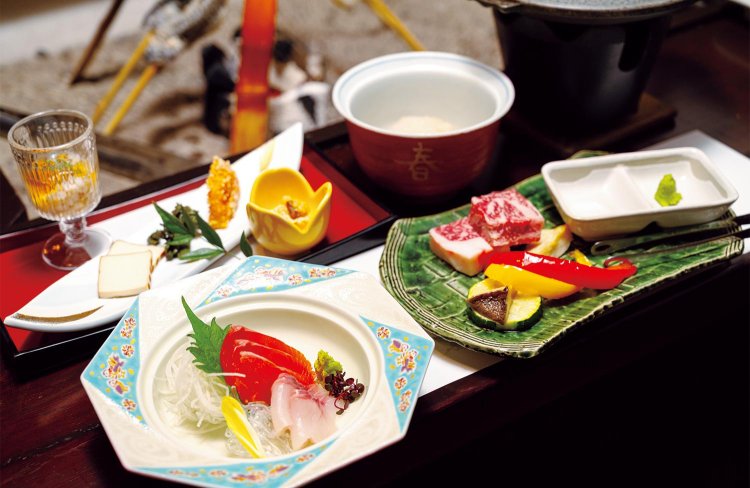 夕食は囲炉裏のテーブルで前菜からスタート。「特選和牛付」のコースは黒毛和牛のミニステーキ（右）が付く。