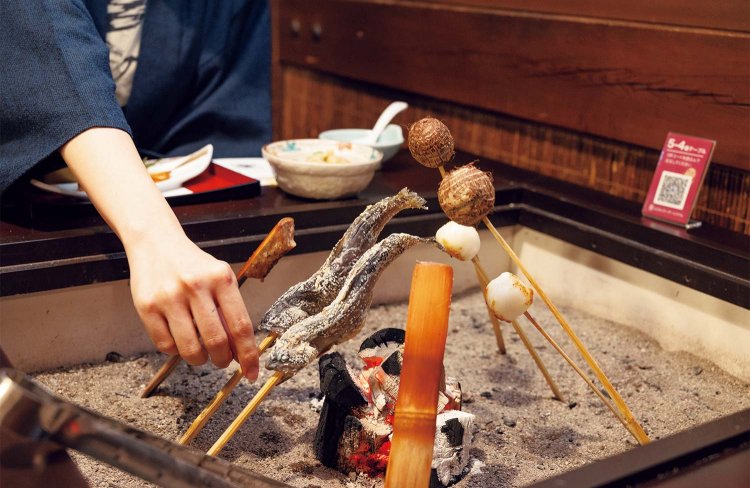 郷土料理の「囲炉裏焼き」。写真左からイワナの塩焼き、一升べら、里芋、米をすりつぶして作られるばんだい餅。