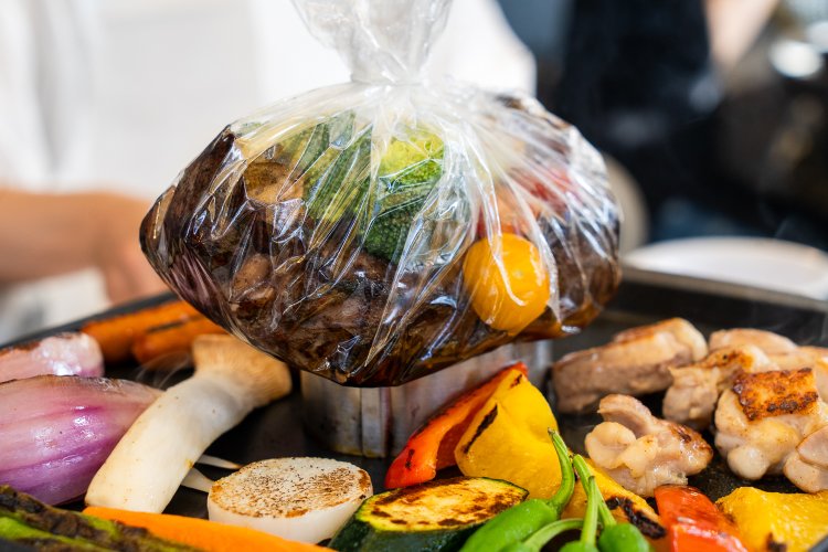 表面を焼いたステーキは野菜と一緒に透明の耐熱シートで包んでセルクルの上に。内部で水分が沸騰するのが見える。