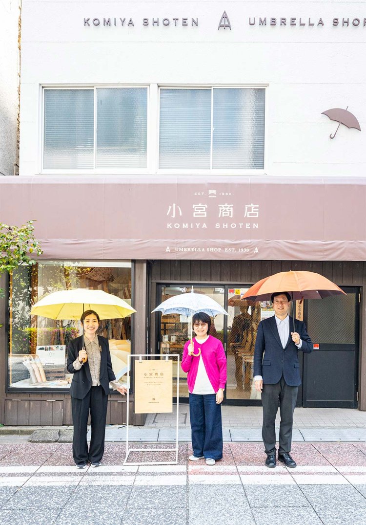 お気に入りの傘を差す、右から小宮社長、コラボ担当の家所さん、広報の加藤さん。