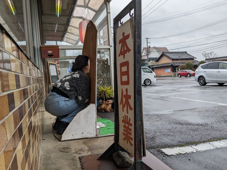 亀山みそ焼きうどんのキャラ「かめみちゃん」の看板。「本日休業」など、裏側だからこその味わい。