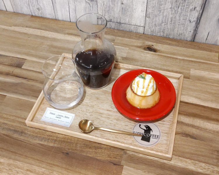 ハンドドリップコーヒーとプリン。トレー左下のシールには、コーヒー豆の産地が記されている。