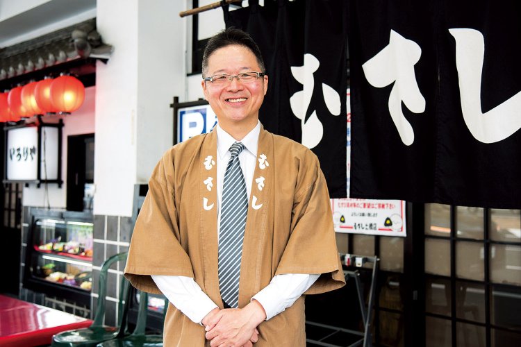 店長の山本伸一さんは入社30年。むすびを握れる社内資格をもつ「むすび人」でもある。「15～16時頃が比較的すいています」。