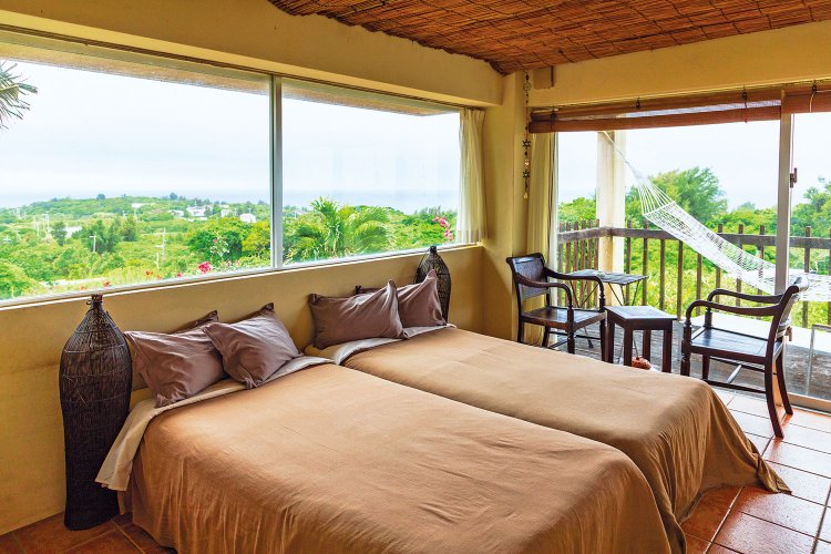 角部屋の2方向に開けた窓や、ハンモックが揺れるバルコニーから、平たい形の瀬底島全 体を見渡せる。空と緑と水平線の大パノラマを独り占め。