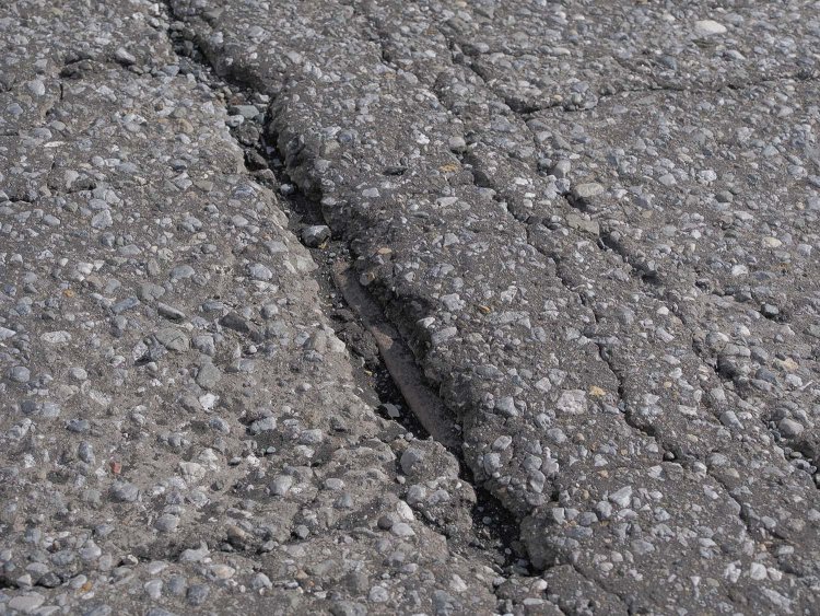 割れたアスファルトの裂け目から露出するレールの頭。