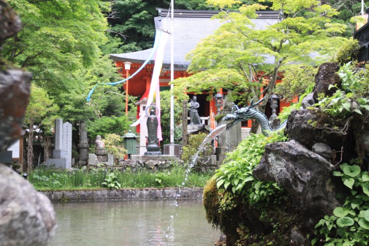 龍の口から湧き出る水を湛えた第一水行場。奥が本堂。
