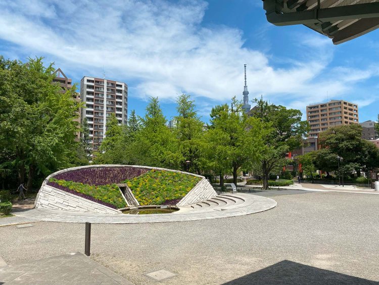 慰霊堂の入り口手前から「東京空襲犠牲者を追悼し平和を祈念する碑」花壇を望む。奥には東京スカイツリー（R）の姿も。