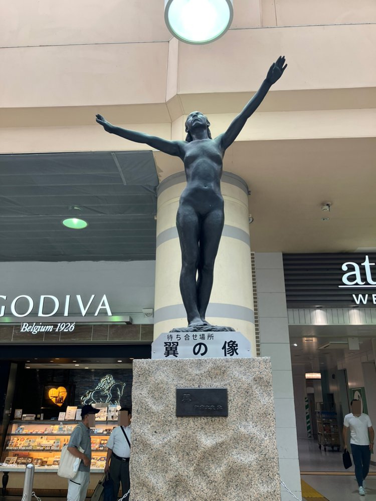 手を伸ばした女性の姿が印象的な「翼の像」。そもそも「待ち合せ場所」と書いてある。