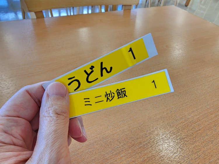 注文メニュー名が書かれたプレートを持って席で待つ。