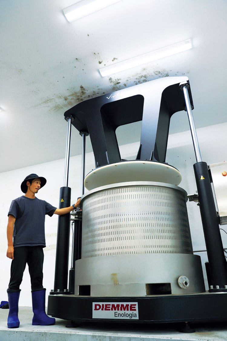 イタリア製の垂直式プレス機と桒原さん。