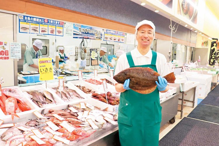 活気が伝わる、魚をさばく手元が見られるオープンな調理場と鮮魚部の小野田修一さん。