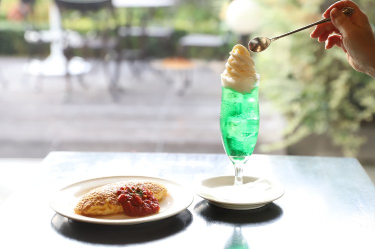 ごはんと卵を生クリームに混ぜリゾットのようにした後、焼き固めるびっくりオムライス（左）。平日はサラダやコーヒーなどがセットで1100円。メロン・フロート980円。