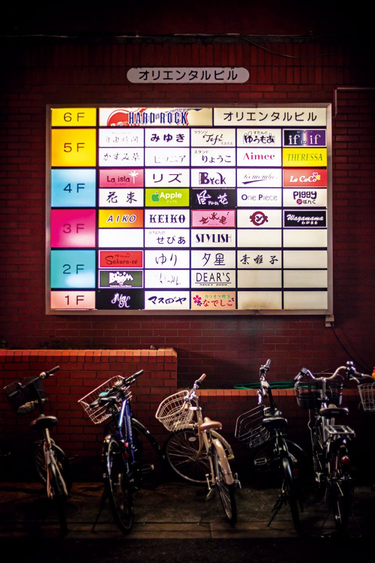 夜を彩る雑居ビルの集合看板。レトロモダンなフォントが目を引く。