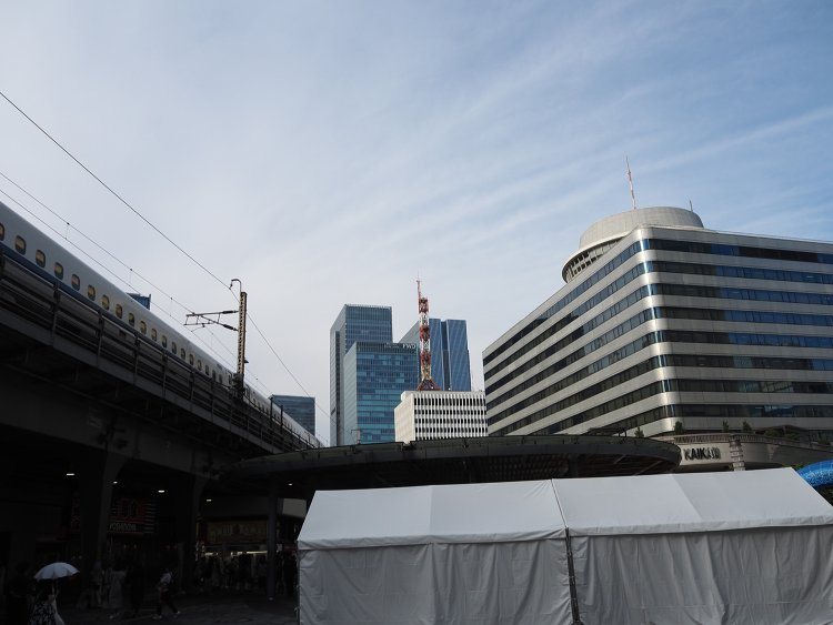 2025年現在の東京交通会館（右）と、通過する東海道新幹線。