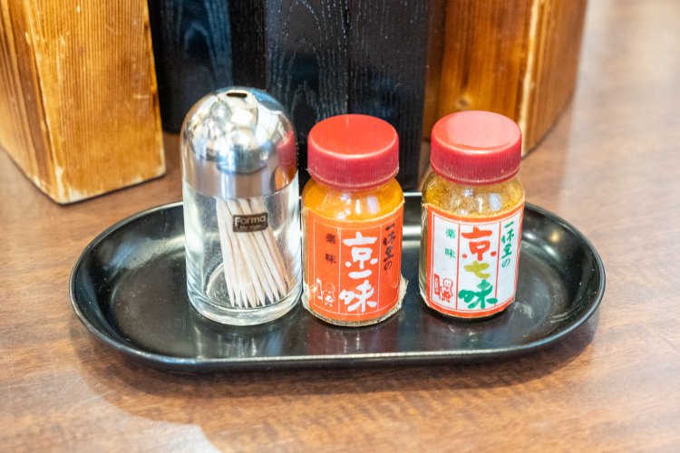 京都『一休堂』の一味と七味。七味は、レンゲにすくった牛かれーうどんのルーに入れると香りが際立つ。