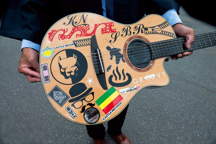 「レゲエ」「 泉 堅」「 ニュージーランド」など、お気に入りのシールを貼った一将さんのギター。