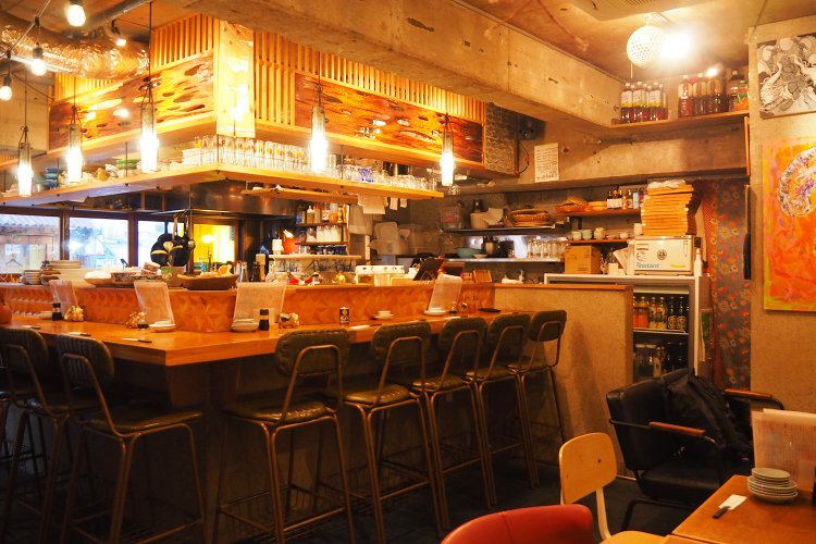 L字のカウンター席と、壁際にテーブル席が並ぶ店内。