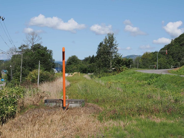幌成（ほろなり）駅のあった方向を見て廃線跡を撮る。ポールの立つ辺りに廃線跡が真っすぐ延びている。