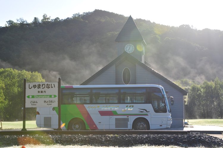 朝日を浴びて駅跡モニュメント前のバス停に深名線バスが停車する（2009年9月撮影）。
