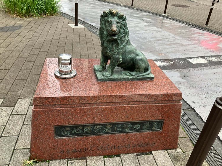 中型犬くらいの大きさのかわいらしいライオン。募金箱も併設されている。