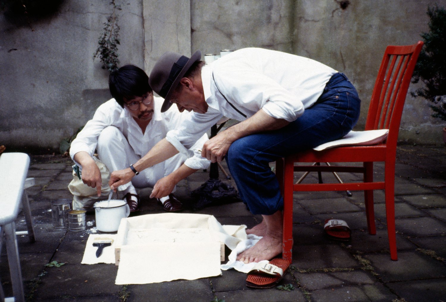 「ヨーゼフ・ボイスの足型を取る若江漢字 デュッセルドルフ、ボイスのアトリエの庭 1983年7月16日」撮影:若江栄戽