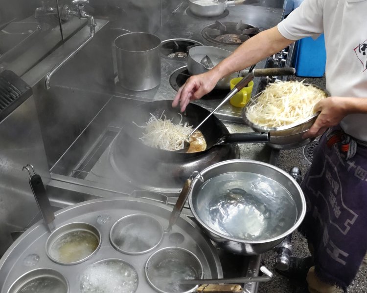 中華鍋にモヤシを加え、さらに炒める。その間、麺が茹で上がるまでの時間をスタッフが逐一報告。