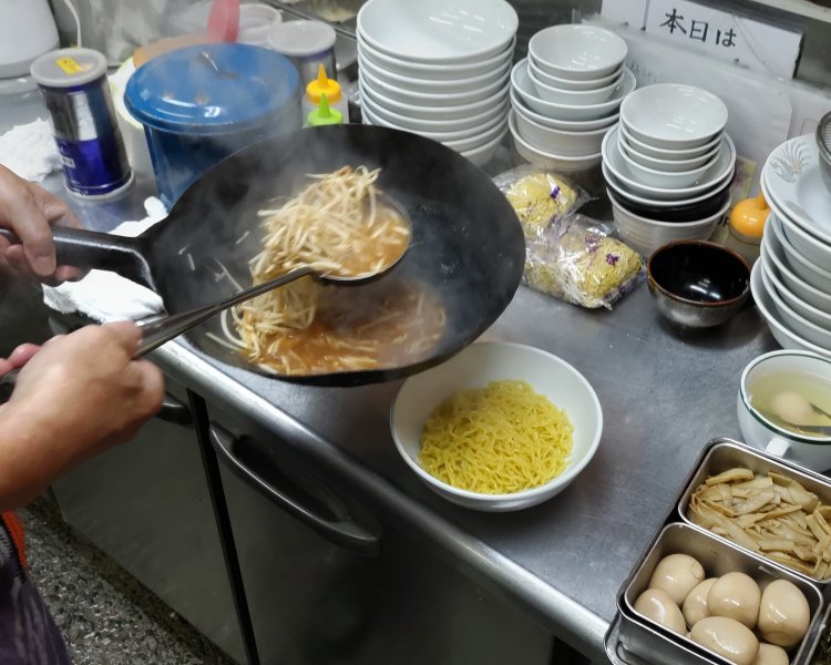先に茹で上がった麺を器へ移しておき、そこに炒めた具材とスープを合わせる。