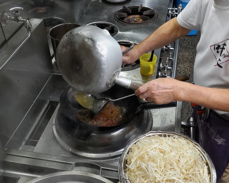炒めた味噌と挽き肉にスープを投入。厨房が熱気に包まれるものの、義弘さんは涼しい表情だ。
