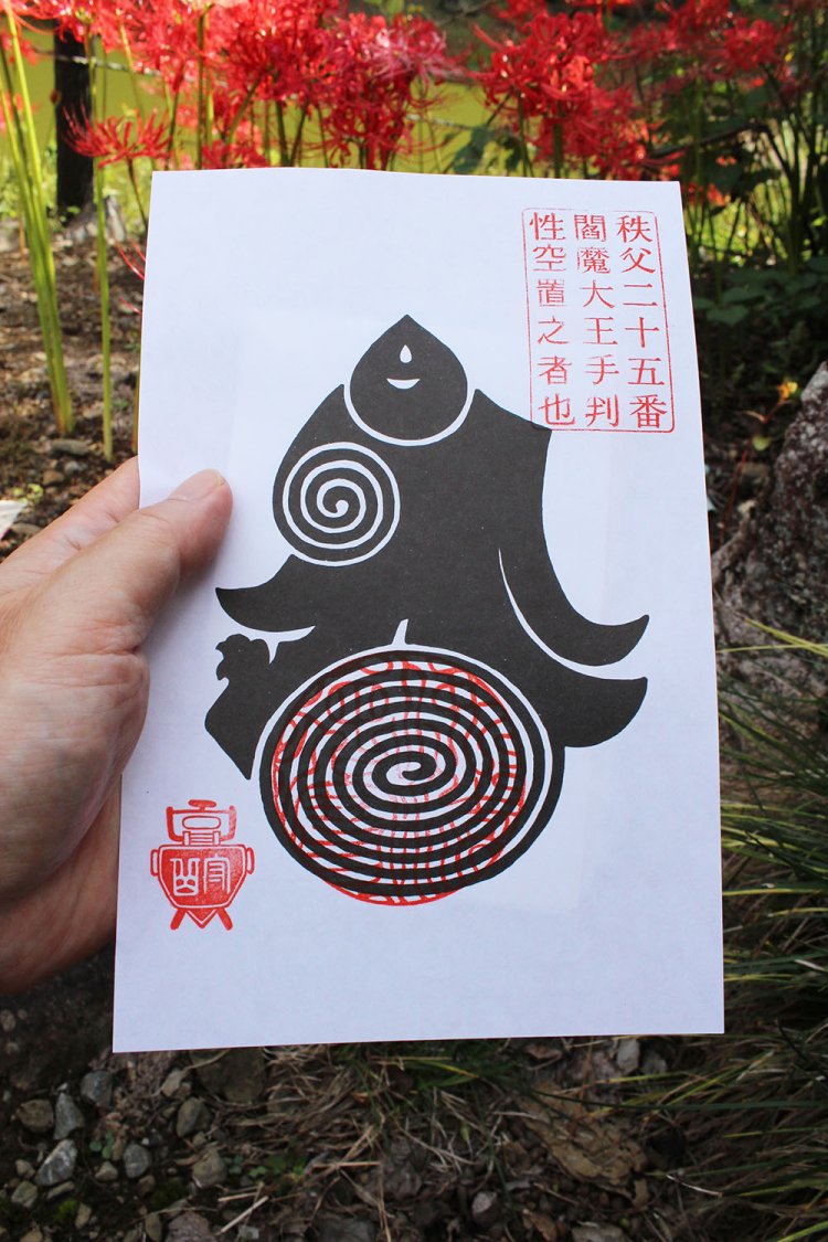 秩父の久昌寺で授与している閻魔大王の御手判。その後ろに地獄花（彼岸花）が咲く。