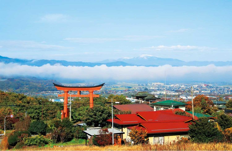 蔵王の朱い大鳥居の奥に、月山や朝日連峰を望む。