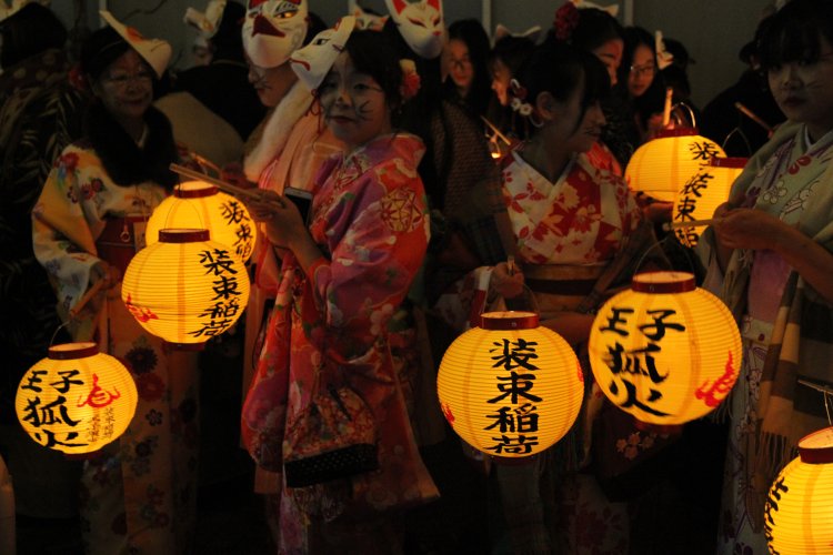 狐に扮した参加者は提灯をかざしながらお囃子（はやし）とともに練り歩く。