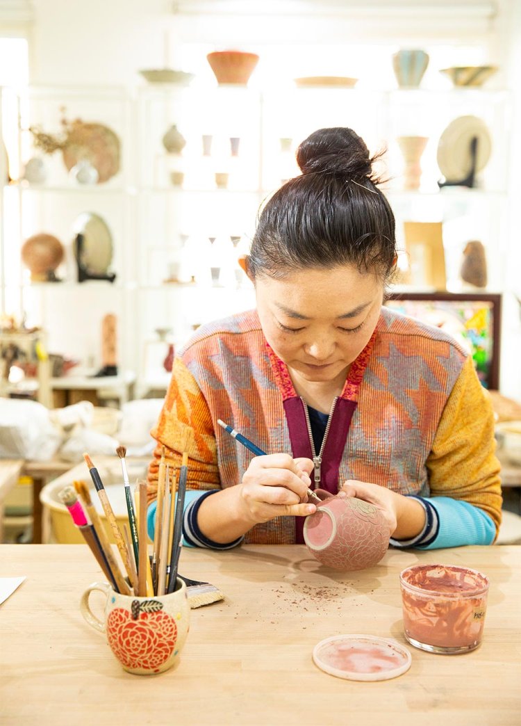 化粧土で盛り上げるイッチン技法や掻き落としなどで装飾を施す理子さん。