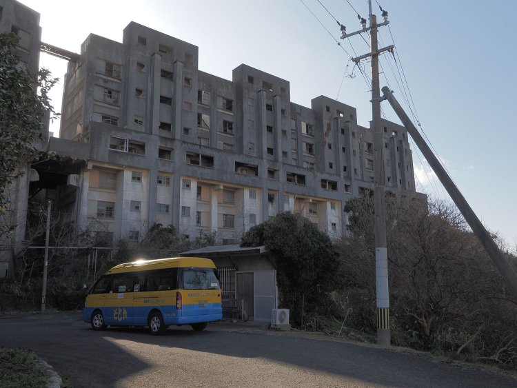 島内唯一のコミュニティバスと廃墟となった8階建て炭鉱アパート。バスは淡々と島内を巡っていた。