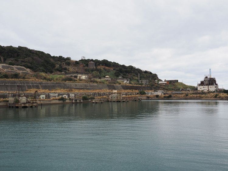 港から見た池島炭鉱遺構。右端は火力発電所跡、円形の建物はシックナー。その手前は貯炭場であった。