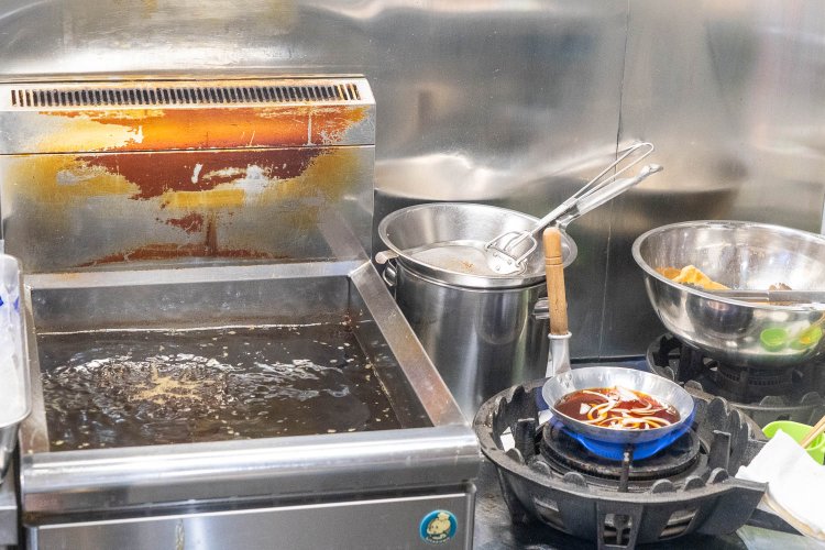 フライヤーの中にはとんかつ。コンロの上には、つゆと玉ねぎが入った親子鍋。