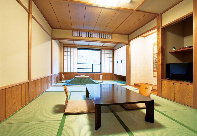 和室10畳に掘りごたつの間が付いた本館和室。窓には雪化粧した甲子山の木々が迫る。