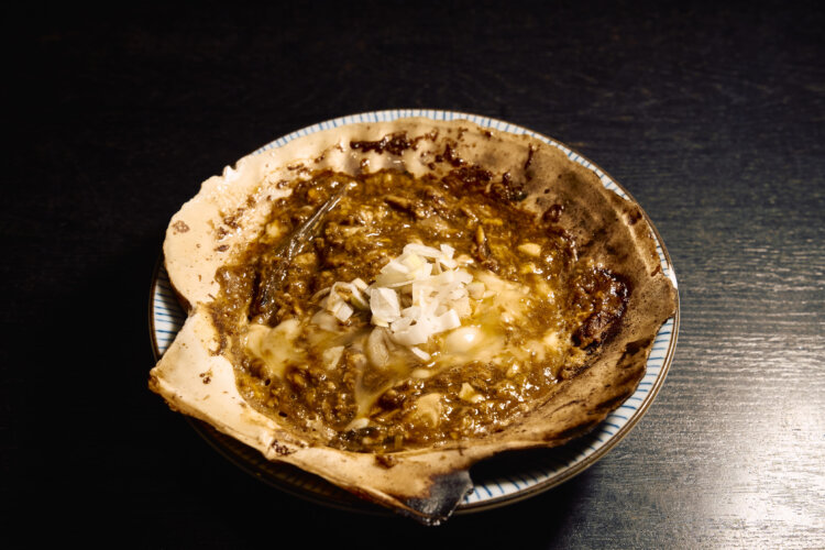 ホタテの貝殻を鍋代わりにしたカヤギ味噌は、卵などの具材を味噌で煮込んだ一品。お酒もご飯も進む。太宰の小説『津軽』にも登場。居酒屋の『磯㐂（いそき）』ではフライパンで作れる貝焼き味噌の素も販売する。