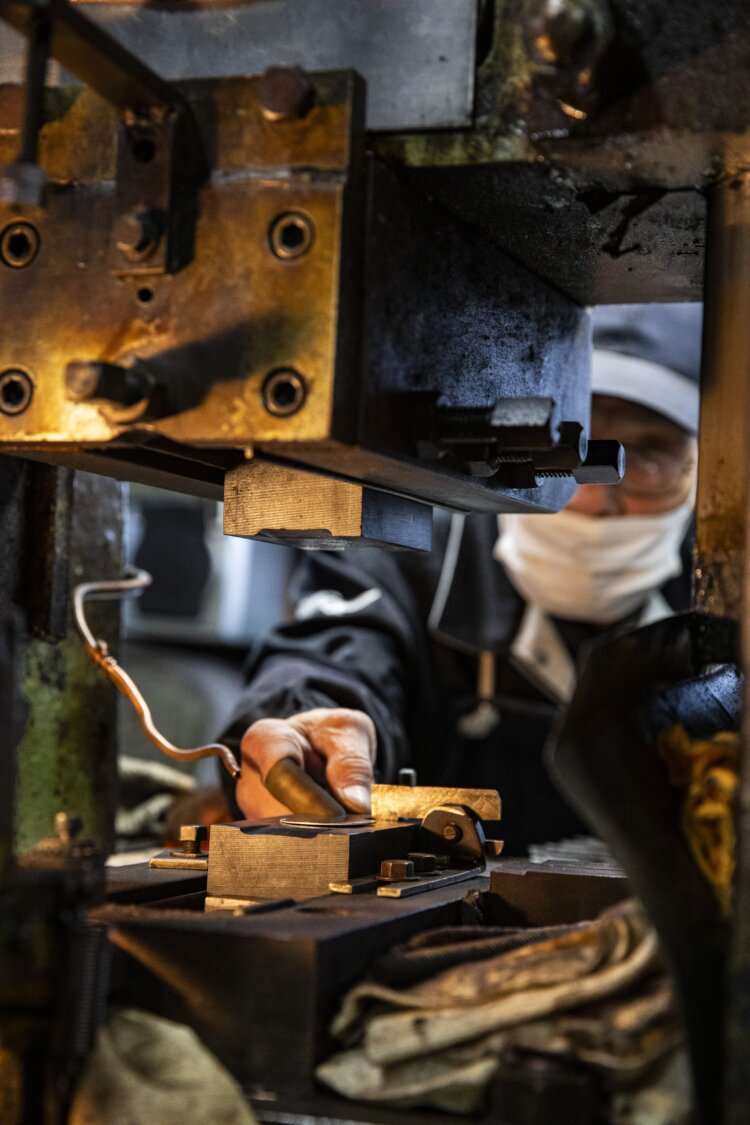 一つ一つプレス機にかけて丸みをつける。磨く場所や角度が異なる研磨機が並び、工程を経るほどに美しい光沢が現れる。