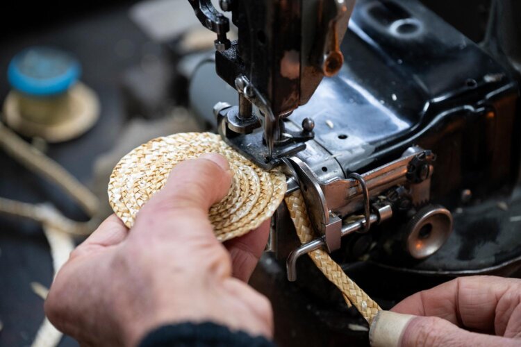 下糸のない環縫いミシンで頂点から渦を巻くように縫い重ねる。縫い始めは製造工程の最難所。