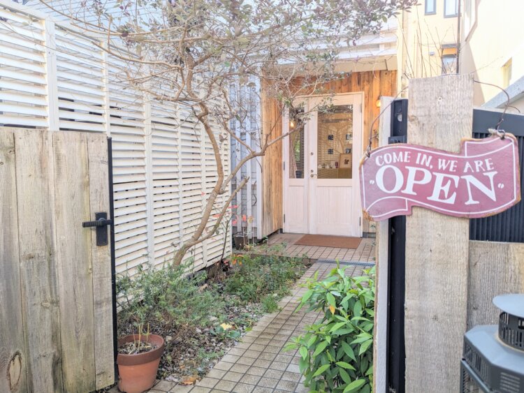 アプローチをたどっていくと、その先にかわいい白い扉が見える。