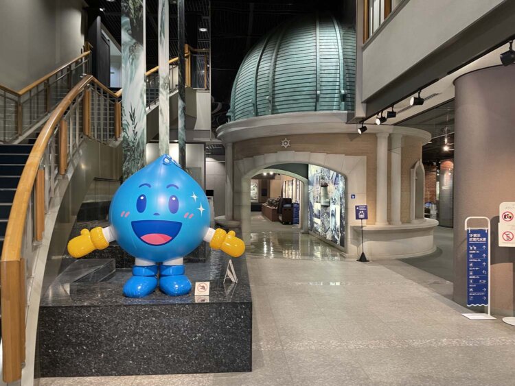 手前左にいるのは「水滴くん」。右手奥に見えるのは取水塔の実物大模型。