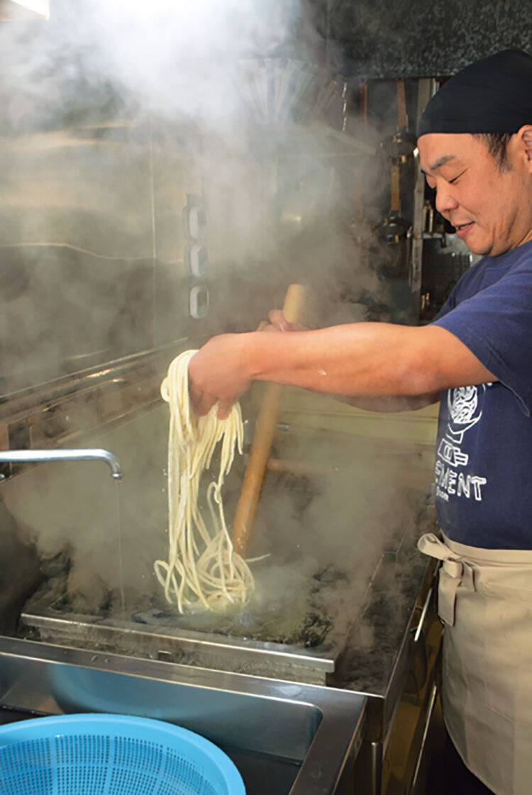 店長の横田仁志さん。釜揚げうどんをつけ麺で味わうのもおすすめです。