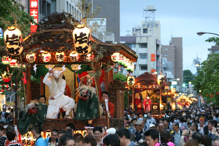夕暮れが迫るなか、提灯の明かりに照らされた山車が連なる様子は幻想的。