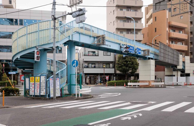 らせん状の歩道橋の脇に「時代屋」はあった。現在は駐車場になっている。歩道橋の名前は「倉田歩道橋」、2026年8月中旬まで塗装工事中。